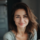 Femme souriante à l'intérieur, ambiance douce.